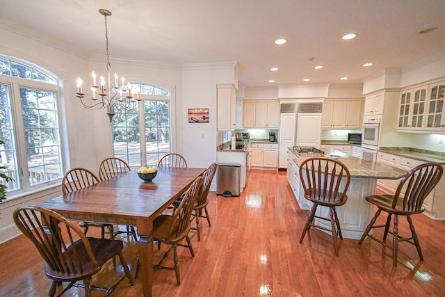 dining area featuring an inviting chandelier, crown molding, and light hardwood / wood-style flooring