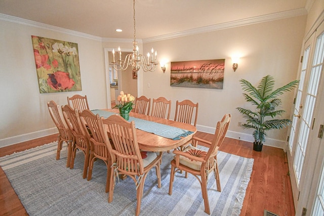 dining space with hardwood / wood-style flooring, ornamental molding, and a chandelier