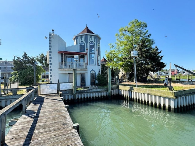 view of dock with a balcony and a water view