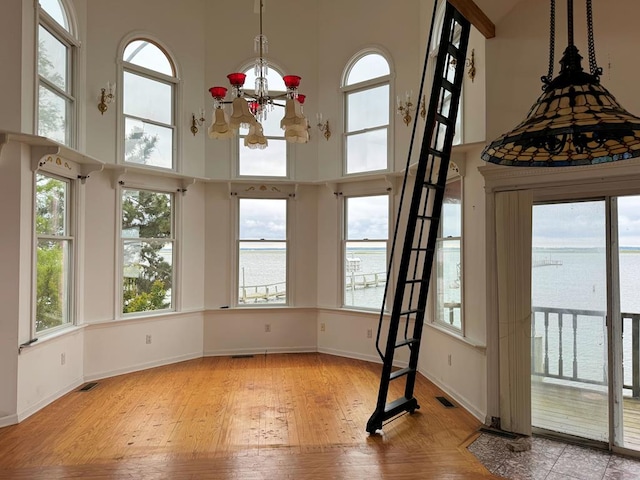 interior space featuring a notable chandelier, plenty of natural light, and a water view