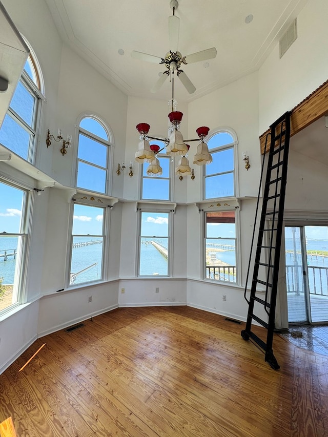 interior space with crown molding, a water view, ceiling fan, and hardwood / wood-style floors