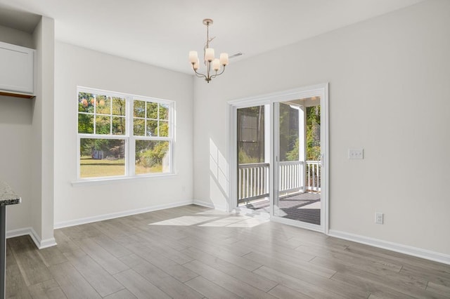 unfurnished dining area featuring hardwood / wood-style flooring and a notable chandelier