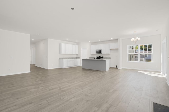 unfurnished living room featuring light wood-type flooring and an inviting chandelier