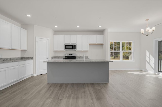 kitchen featuring stainless steel appliances, white cabinetry, and a center island with sink