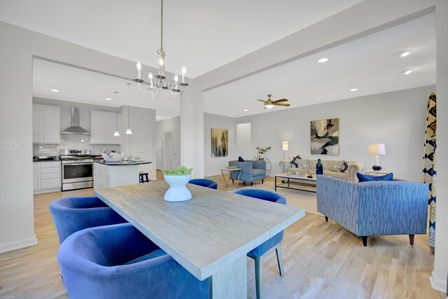 dining space featuring ceiling fan with notable chandelier and light hardwood / wood-style flooring