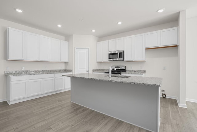 kitchen featuring a center island with sink, white cabinetry, and appliances with stainless steel finishes