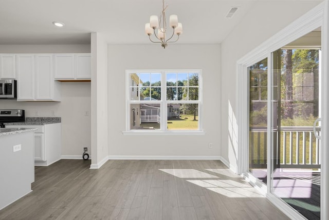 unfurnished dining area with a chandelier and light hardwood / wood-style floors