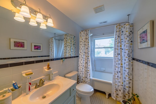 full bath featuring toilet, vanity, visible vents, tile walls, and tile patterned floors