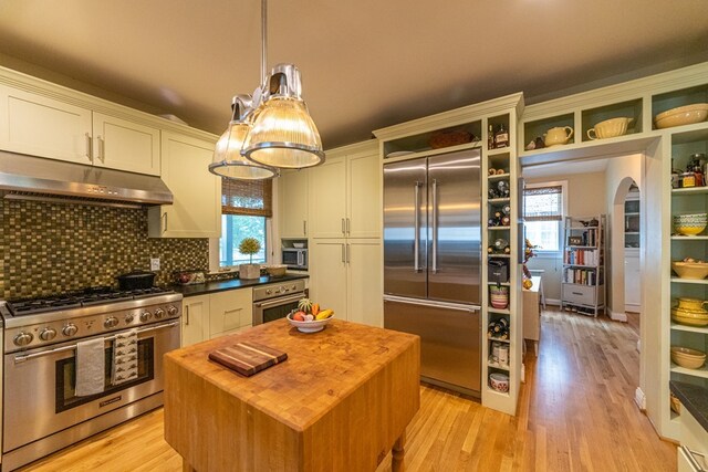 kitchen featuring stainless steel appliances, light wood-style floors, under cabinet range hood, and wood counters