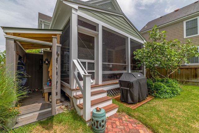 exterior space featuring a sunroom, a grill, and fence