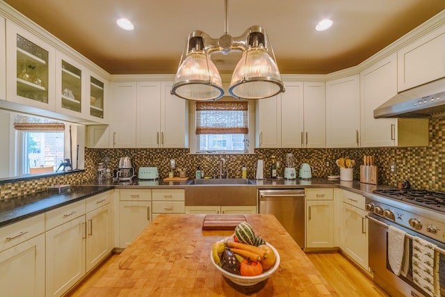 kitchen with a healthy amount of sunlight, tasteful backsplash, wood counters, and appliances with stainless steel finishes