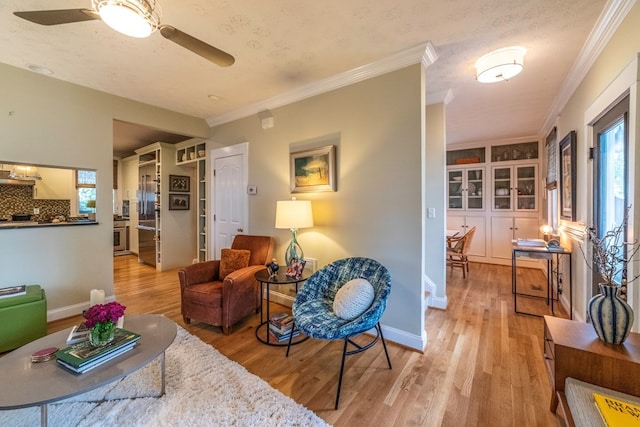 living room with ornamental molding, light wood-type flooring, and a ceiling fan