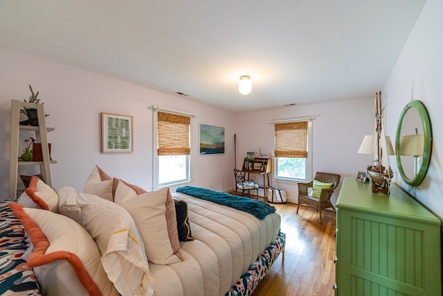 bedroom with wood finished floors, visible vents, and baseboards