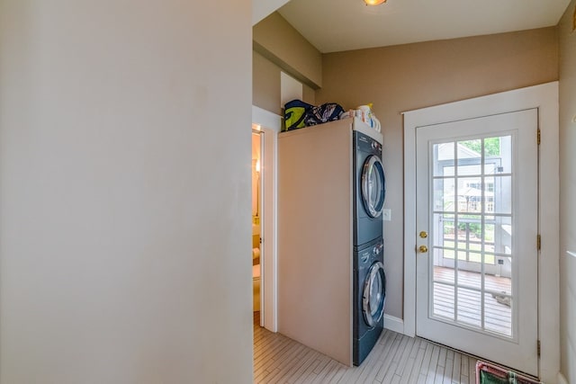 laundry area with laundry area, light wood-style flooring, and stacked washer and clothes dryer