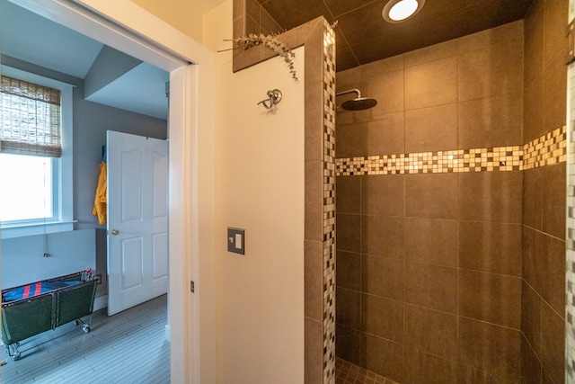 full bathroom featuring a tile shower and wood finished floors