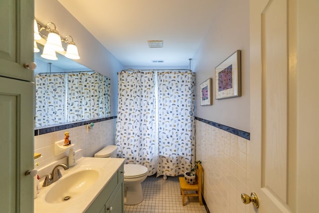 full bath with toilet, tile patterned flooring, tile walls, and vanity