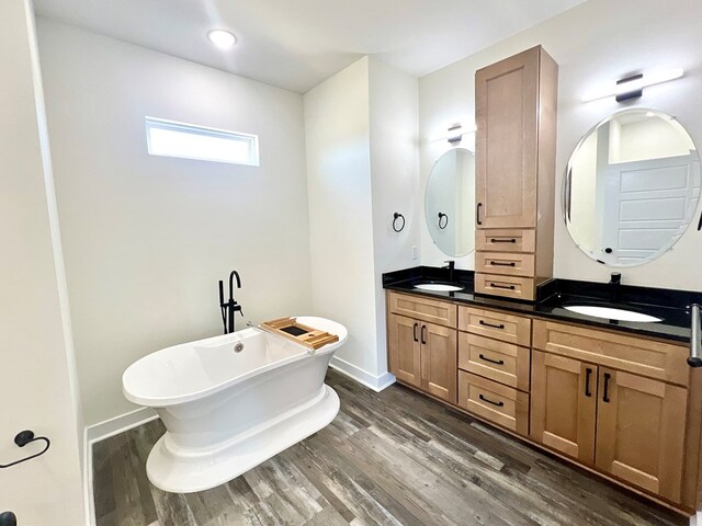 37734 Blue Crab Cir, Painter, VA 23420 - full bathroom featuring a soaking tub, double vanity, wood finished floors, and a sink