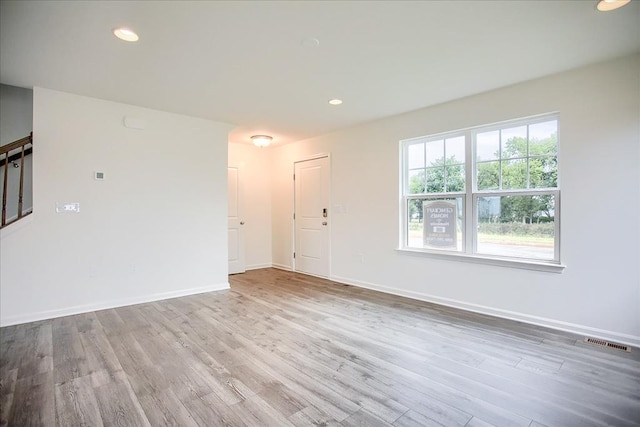 empty room featuring light wood-style floors, baseboards, stairway, and recessed lighting