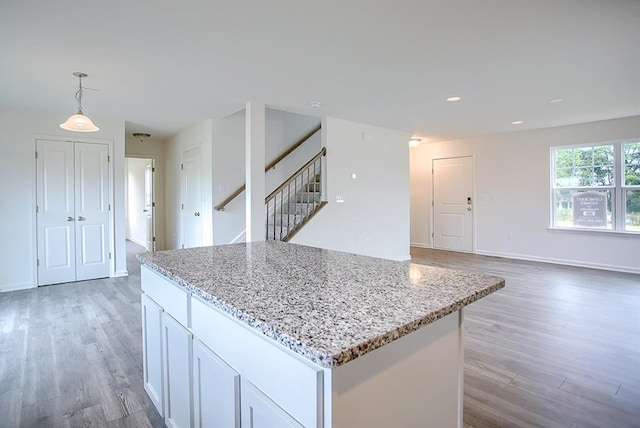 kitchen featuring light stone countertops, wood finished floors, decorative light fixtures, and white cabinetry