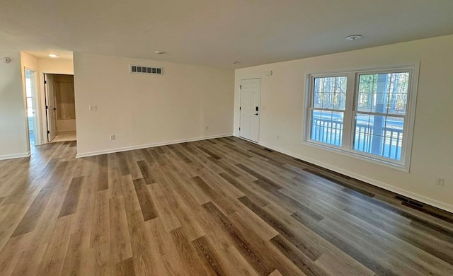 unfurnished room featuring visible vents, baseboards, and wood finished floors