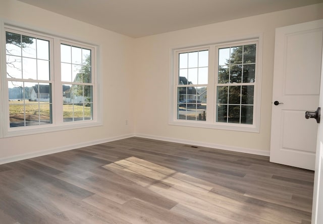 empty room featuring visible vents, baseboards, and wood finished floors