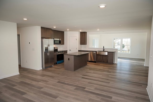 kitchen with stainless steel appliances, open floor plan, a sink, and dark brown cabinetry