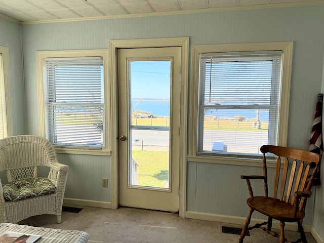 doorway with crown molding, light colored carpet, and a water view