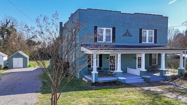 view of front of house with covered porch, a shed, and a front yard