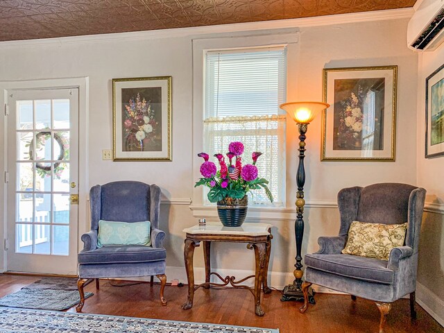 sitting room with hardwood / wood-style floors, an AC wall unit, and crown molding