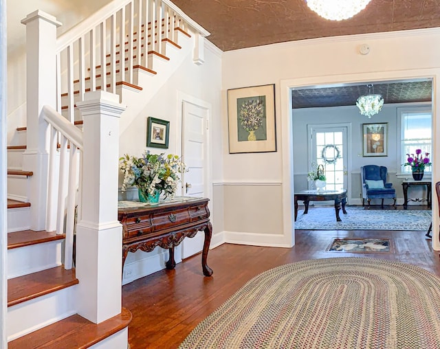 entrance foyer with dark hardwood / wood-style floors, an inviting chandelier, ornamental molding, and ornate columns