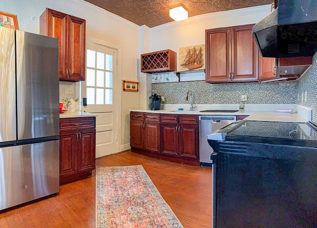 kitchen with decorative backsplash, appliances with stainless steel finishes, ornamental molding, ventilation hood, and light hardwood / wood-style flooring