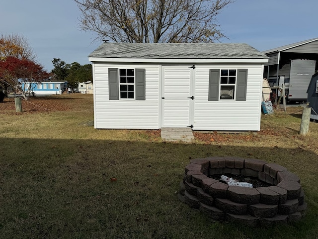 view of outbuilding with a yard and a fire pit