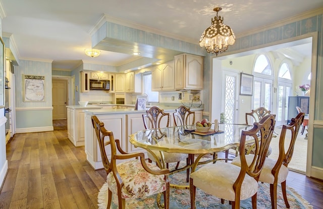 dining space featuring ornamental molding, plenty of natural light, wood-type flooring, and a notable chandelier