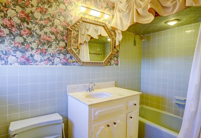 full bathroom with vanity, toilet, tile walls, and shower / bath combo with shower curtain