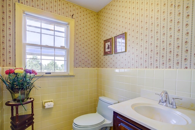 bathroom featuring vanity, toilet, and tile walls