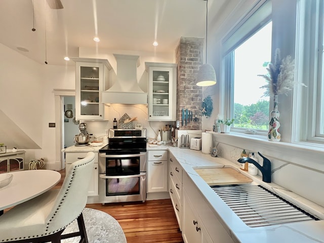 2453 Sand Hill Dr, Cape Charles, VA 23310 - kitchen with range with two ovens, premium range hood, dark wood-style floors, hanging light fixtures, and white cabinetry