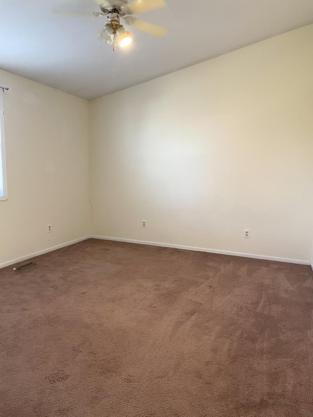 empty room with ceiling fan and dark colored carpet