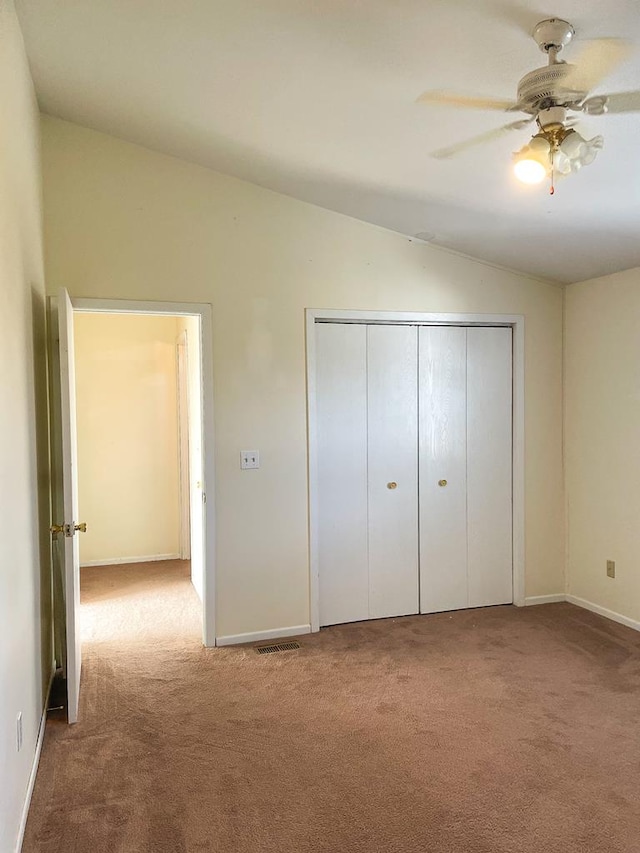 unfurnished bedroom featuring ceiling fan, light colored carpet, lofted ceiling, and a closet