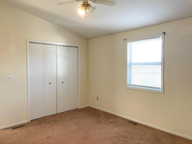 unfurnished bedroom with light carpet, a closet, vaulted ceiling, and ceiling fan