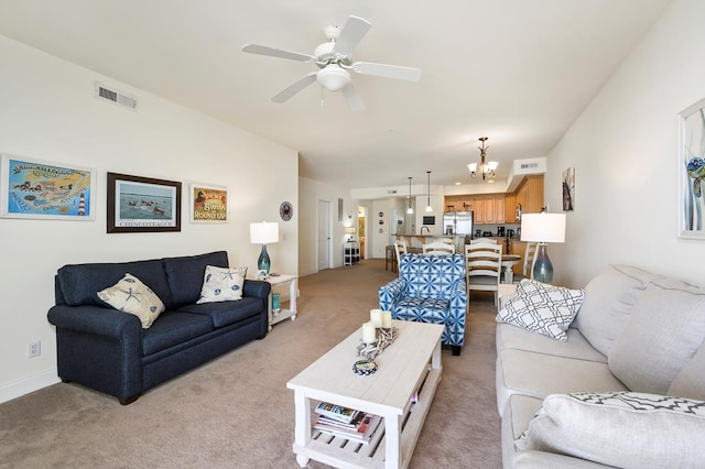 living room featuring ceiling fan with notable chandelier and light colored carpet