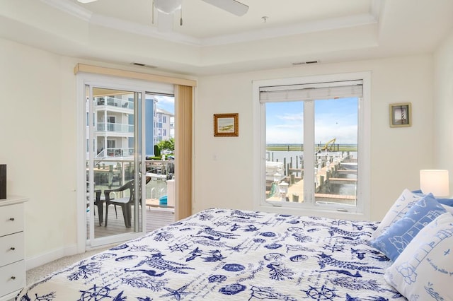 bedroom featuring carpet flooring, ceiling fan, a raised ceiling, access to outside, and a water view