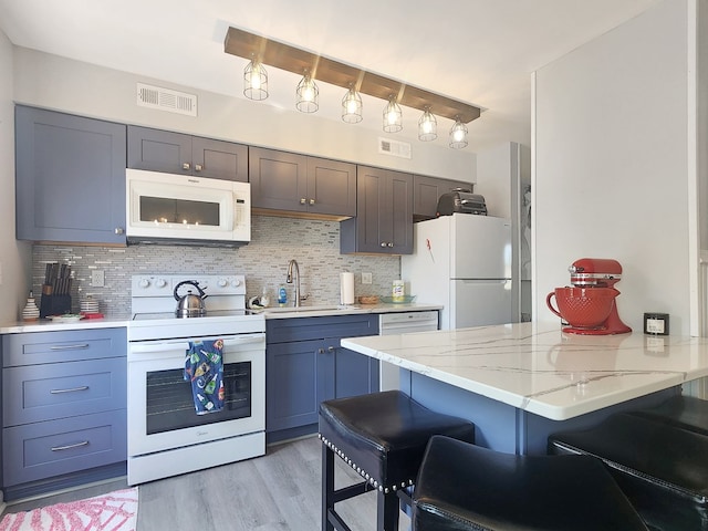 7207 Bunting Rd, Chincoteague, VA 23336 - kitchen featuring white appliances, a sink, tasteful backsplash, a breakfast bar, and light wood-style floors