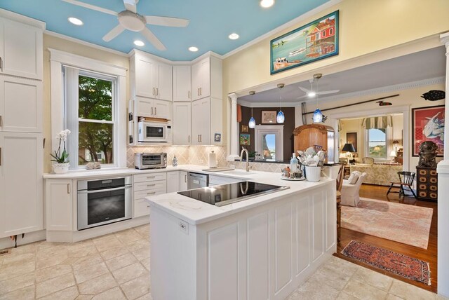 306 Bay Ave, Cape Charles, VA 23310 - kitchen featuring stainless steel appliances, a ceiling fan, a peninsula, ornamental molding, and white cabinets
