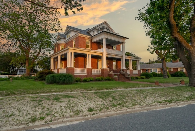 306 Bay Ave, Cape Charles, VA 23310 - greek revival house featuring a porch, brick siding, a balcony, and a front yard