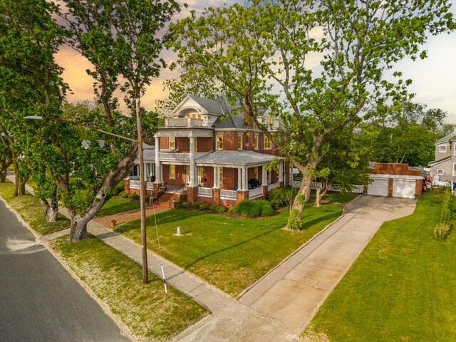 306 Bay Ave, Cape Charles, VA 23310 - neoclassical home featuring a balcony, covered porch, a lawn, and concrete driveway