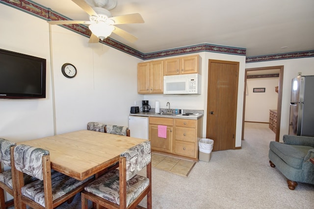 kitchen featuring ceiling fan, light brown cabinets, light colored carpet, and white appliances