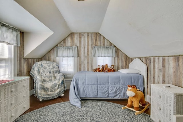 bedroom featuring lofted ceiling, dark wood-type flooring, and wooden walls