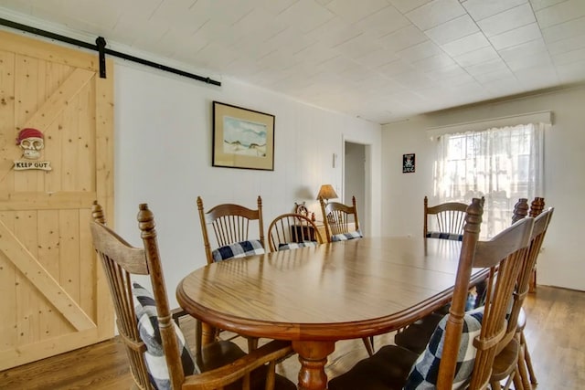 dining area with a barn door, hardwood / wood-style floors, and wooden walls