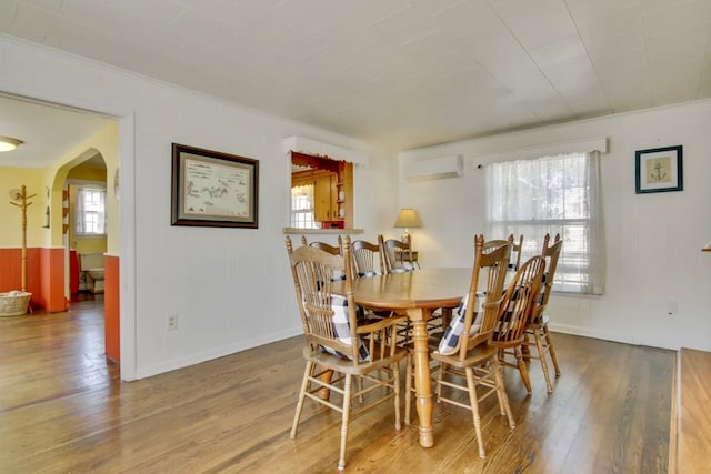 dining space with wood-type flooring and an AC wall unit