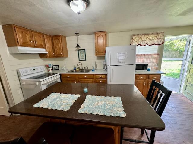 kitchen with light wood-type flooring, sink, white appliances, and decorative light fixtures